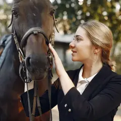 Une jeune femme caresse un cheval, prête pour le sport équestre.