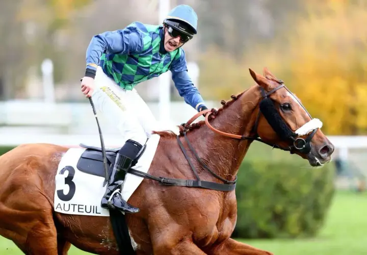 Un jockey en tenue bleue et verte, sur un cheval bai portant le numéro 3 "Auteuil", sprinte vers la victoire.
