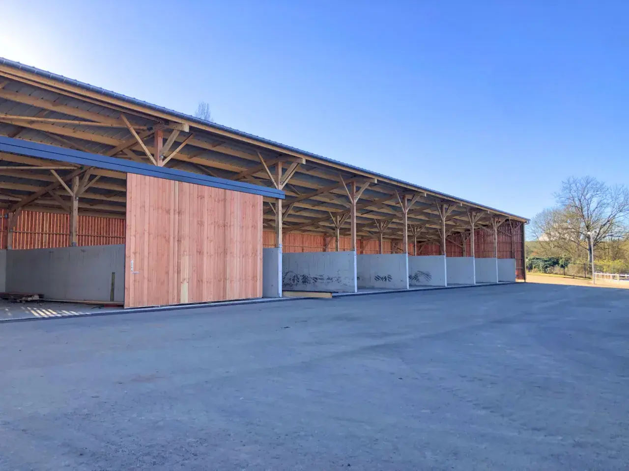 Structure en bois et béton pour construire une fumière. Les murs en béton sont déjà en place, prêts à recevoir le compost.
