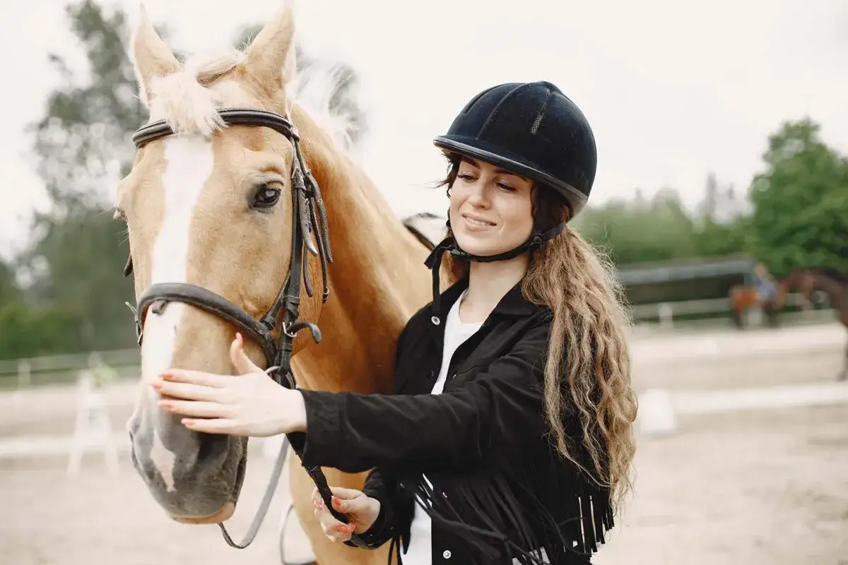 Une cavalière souriante caresse son cheval. Quel galop pour avoir un cheval aussi beau !